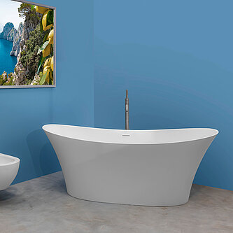 Ein blau gestrichenes Badezimmer mit einer freistehenden Badewanne aus dem samtweichen SolidSurfce-Material und einem Bidet sowie WC jeweils mit einer matten chromfarbenen Armatur und einem wunderschönen Bild aus Italien, dass an der Wand hängt