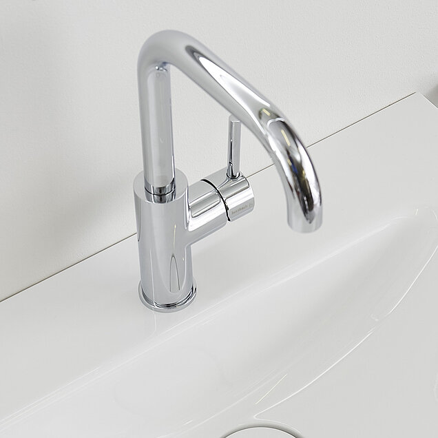 Ein moderner Chrom-Wasserhahn auf einem weißen Waschbecken 
