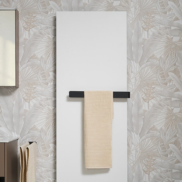 Ausschnitt eines Badezimmers in dem der LARIMAR Designheizkörper inklusive Handtuchbügel gezeigt wird, andem ein beiges Handtuch hängt