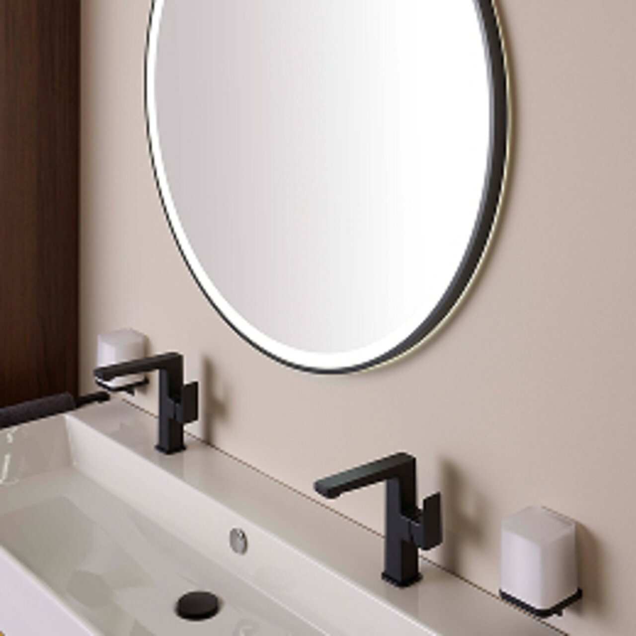 Ein modernes Waschbecken mit schwarzen Armaturen, einem großen runden Spiegel mit beleuchtetem Rand