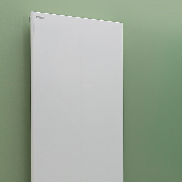 Weißer schlichter Badheizköprer an einer hellen Wand angebracht.