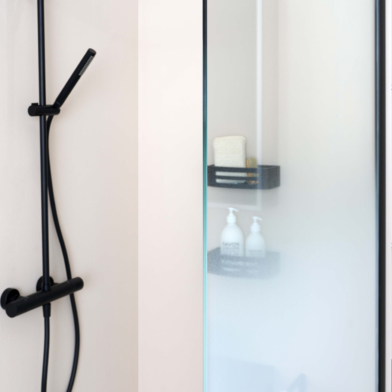 Eine moderne Dusche mit einer mattschwarzen Handbrause und passenden Bedienelementen