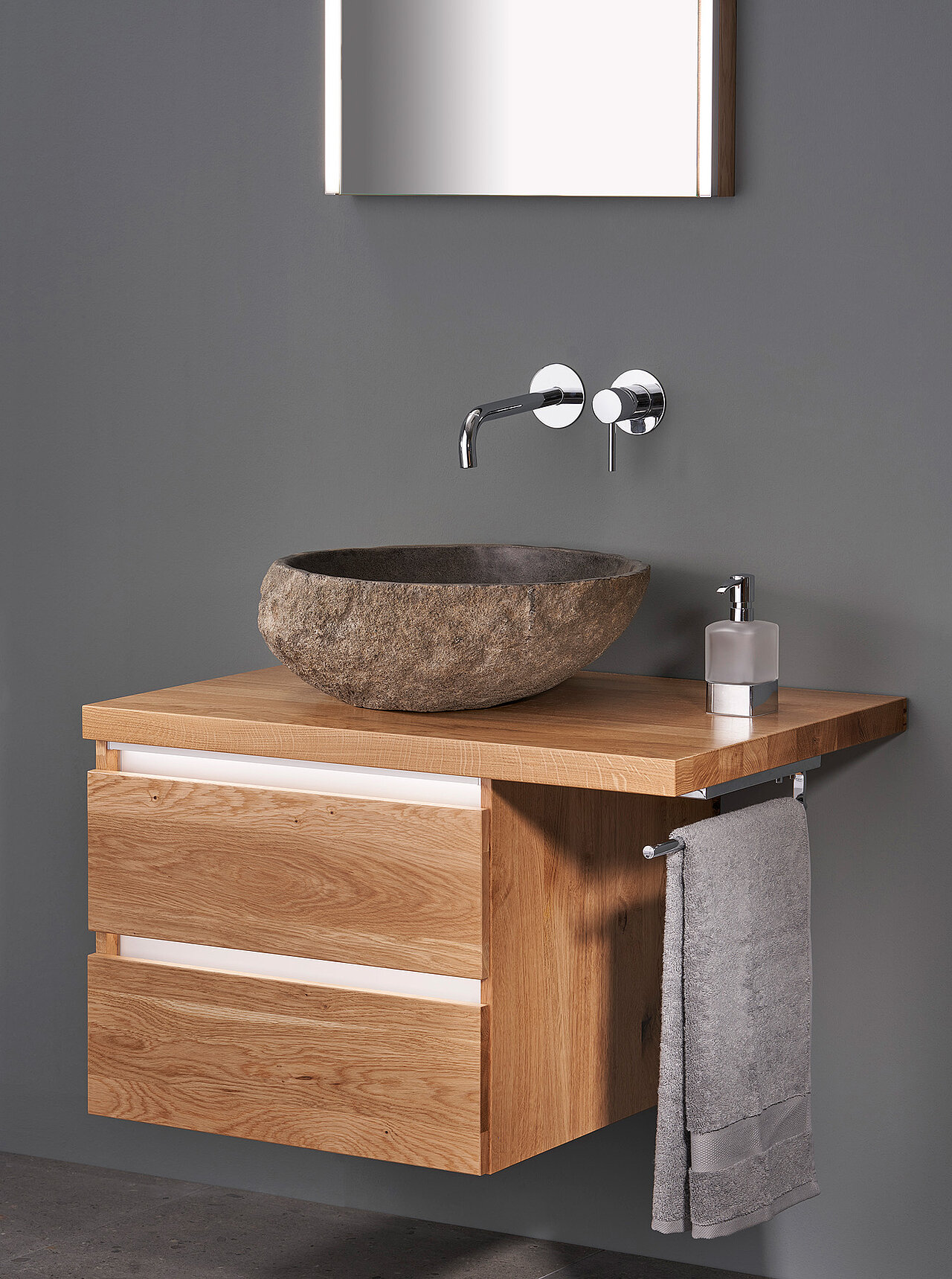 Ein moderner Badezimmer-Waschtisch mit einem Holzschrank, einem Waschbecken aus Stein, einem wandmontierten Wasserhahn