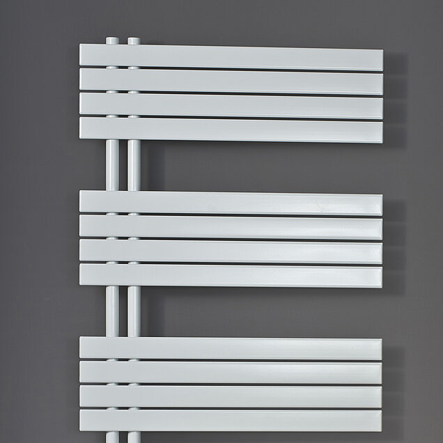 Ein moderner, horizontaler weißer Heizkörper mit flachen Platten, der an einer grauen Wand montiert ist. 