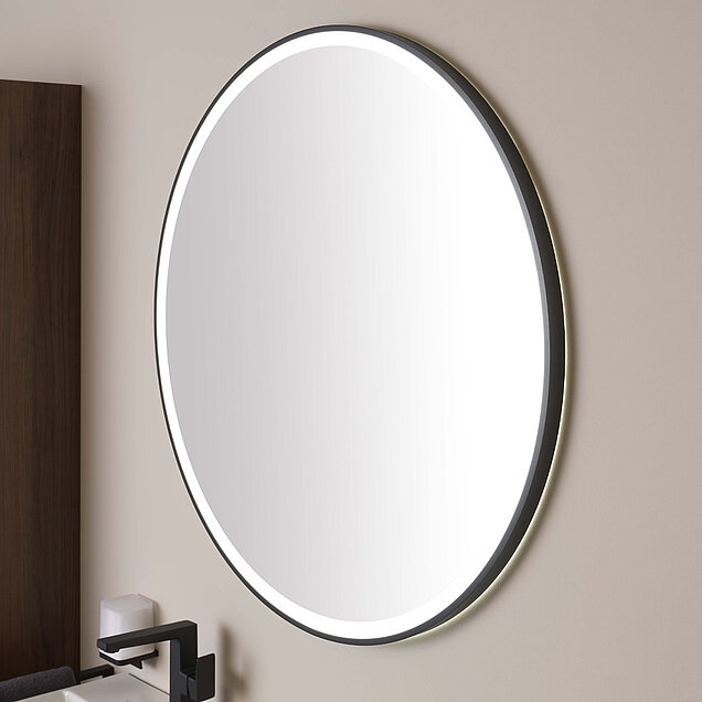 Ein großer, runder Wandspiegel mit schwarzem Rahmen und eingebauter LED-Hintergrundbeleuchtung.