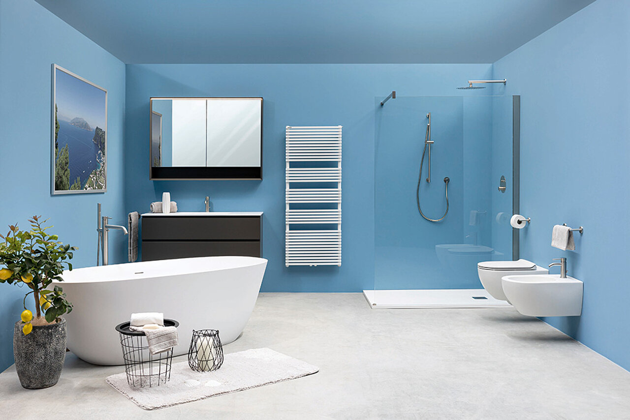 Badezimmer mit blauen Wänden, einer weißen freistehenden Badewanne, einem Wandwaschbecken mit Spiegel, einem Handtuchwärmer.