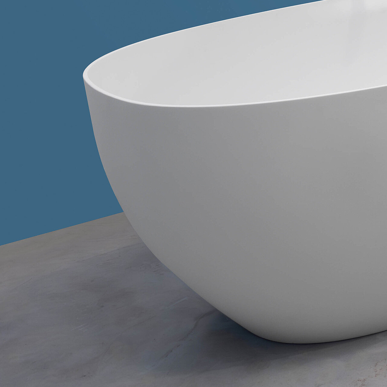 Neue Larimar CAPRI Badewanne mit modernen Rundungen und grauer samtweichem Oberflächenmaterial names SolidSurface ist freistehend im Raum montiert mit einer matten chromfarbenen Standarmatur in einem blau gestrichenen Badezimmer welches mit schwarzen Badmöblen einem Siegelschrank und einer Handtuchheizung kombiniert ist.