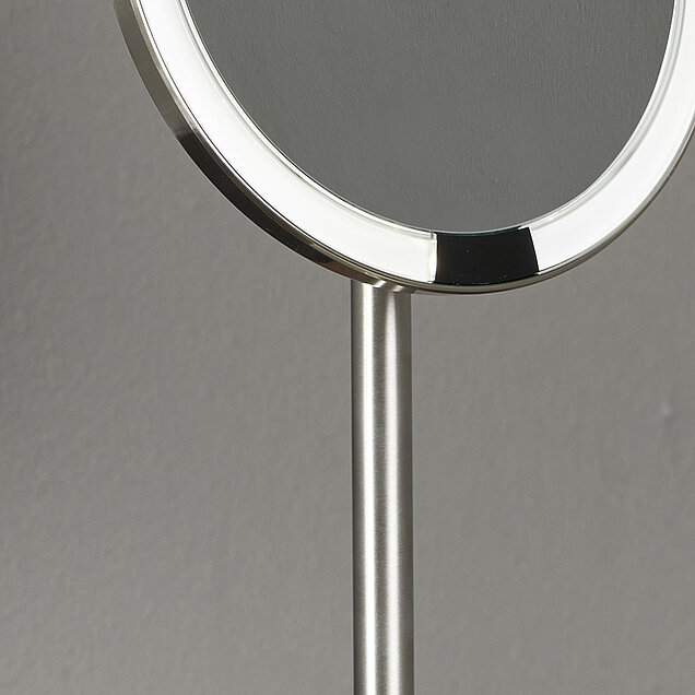 Nahaufnahme eines runden Tischspiegels mit silbernem Rahmen und eingebauter LED-Beleuchtung am Rand