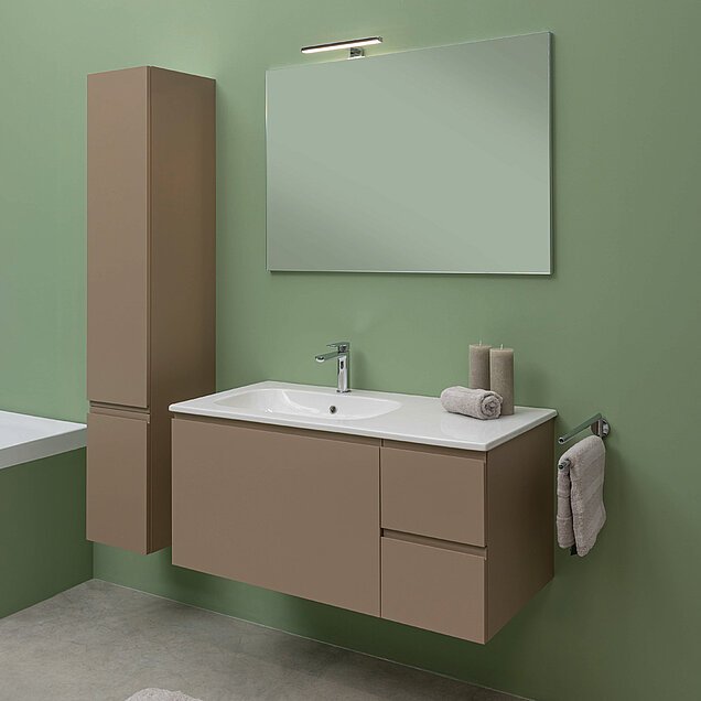 Badezimmer mit grünen Wänden, einem großen rechteckigen Spiegel, einem braunen, schwebenden Waschtisch mit einem weißen Waschbecken und ein Schrank.