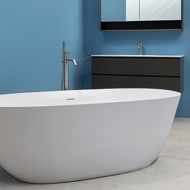 Ein modernes Badezimmer mit einer freistehenden weißen Badewanne, einem mattschwarzen Waschtisch mit Waschbecken