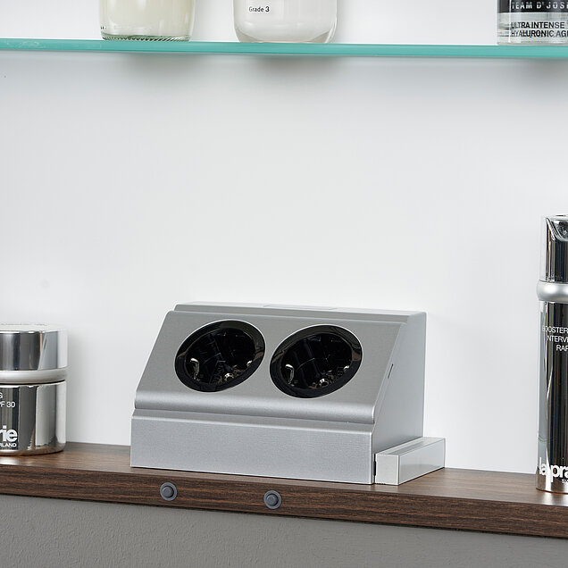 Ein Detail des LARIMAR Wandeinbauspiegelschranks, dass die integrierte Steckdosenleiste zeigt.