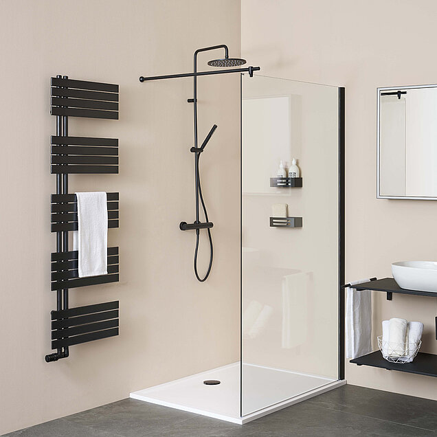 Badezimmer mit einer begehbaren Dusche mit schwarzem Duschkopf und Armaturen, Glastrennwand, modernem schwarzen Handtuchheizkörper