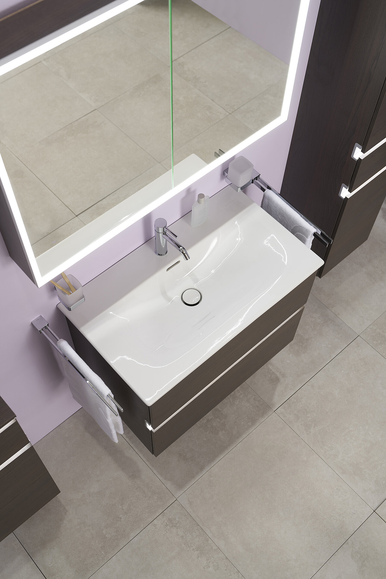 Sicht von oben auf ein Badezimmerwaschbecken mit rechteckigem weißem Becken, verchromtem Wasserhahn und Waschtisch aus dunklem Holz.