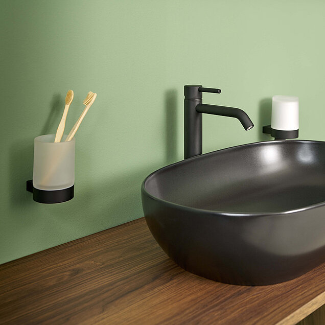 Badezimmer mit einem mattschwarzen ovalen Waschbecken, einem schwarzen Wasserhahn, einer hölzernen Arbeitsplatte.