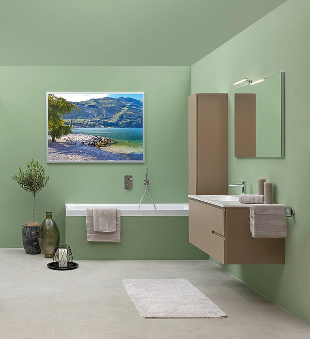 Badezimmer mit grünen Wänden, einem schwebenden beigen Waschtisch, einer freistehenden Badewanne, einem Wandspiegel.