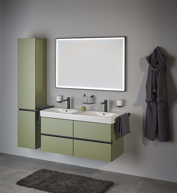 Badezimmer mit olivgrünen, schwebenden Schränken, Doppelwaschbecken und einem großen beleuchteten Spiegel.