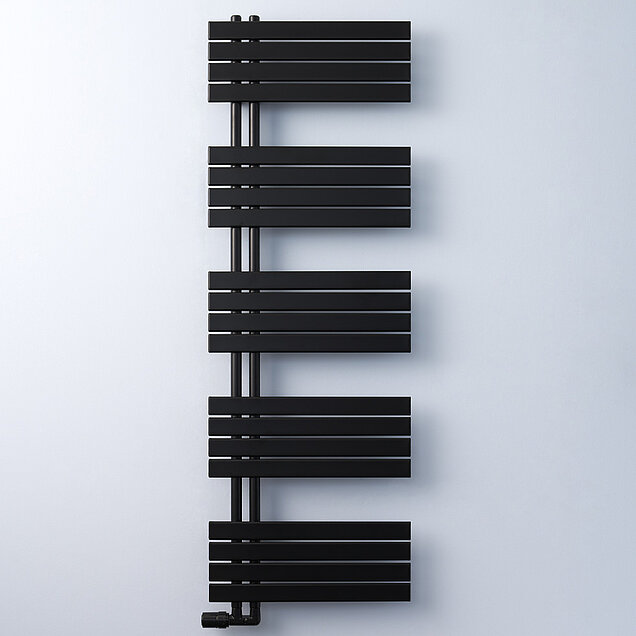 Ein moderner, schwarzer Badheizkörper vor einer schlichten, hellen Wand. 