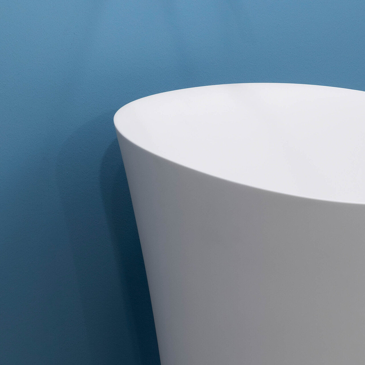 Eine blaue Wand im Hintergrund und ein freistehendes modernes Waschbecken der Produktlinie LARIMAR CAPRI