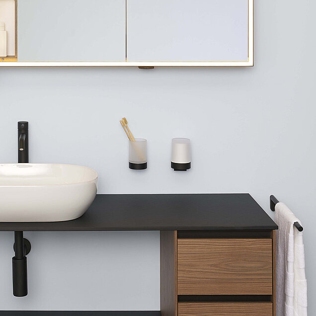 Waschtisch mit weißem Waschbecken, schwarzem Wasserhahn, hölzernen Schubladen und einer schwarzen Arbeitsplatte. 