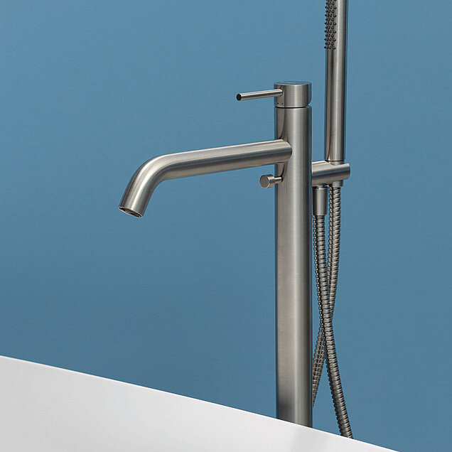 Badewannenarmatur aus gebürstetem Metall und eine Handbrause sind neben einer weißen Badewanne installiert