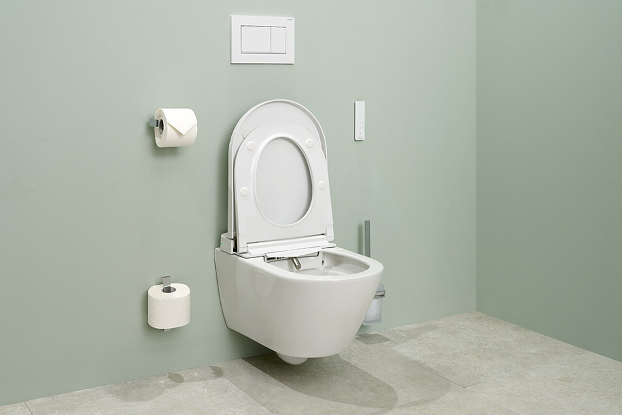 Modernes Dusch-WC mit hochgeklapptem Deckel an einer grünen Wand