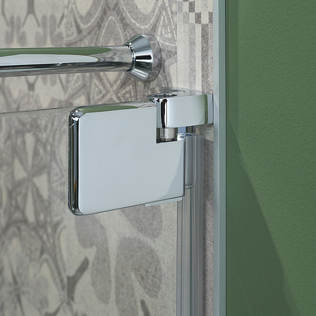 Nahaufnahme eines glänzenden Chromscharniers, das an einer gläsernen Duschtür befestigt ist